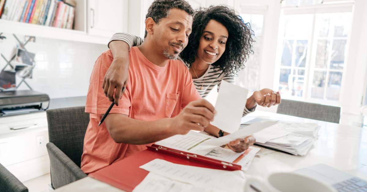 Happy couple reviewing budget plans for affordable house construction in South Africa.