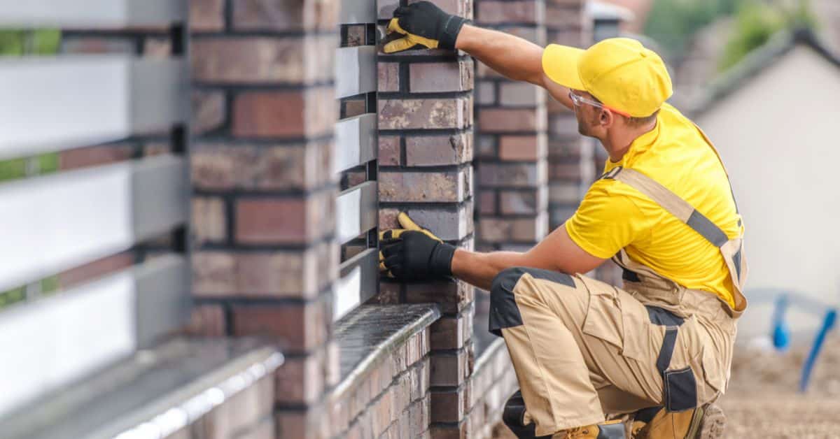 Construction worker laying bricks for affordable house building in South Africa.