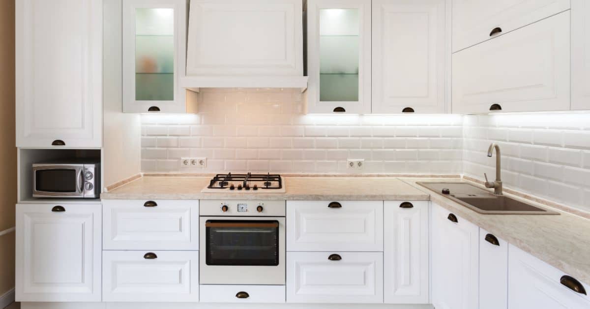 Kitchen with white cabinets, built-in oven, microwave, and sleek countertops.