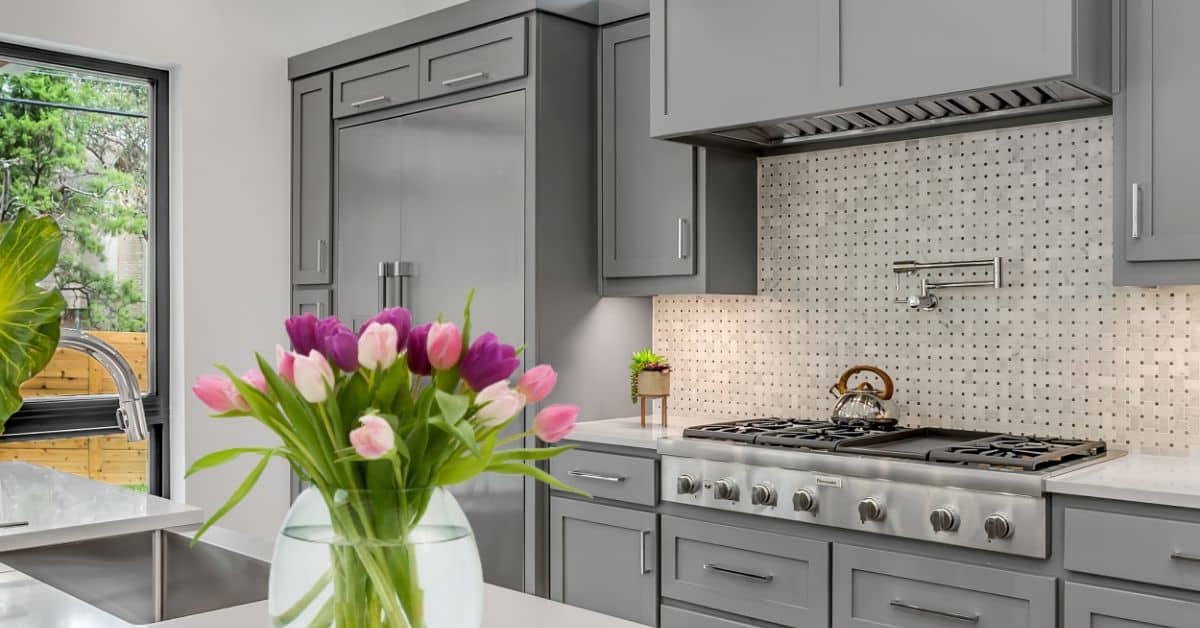 Modern gray kitchen with a bouquet of pink and purple tulips on the countertop.