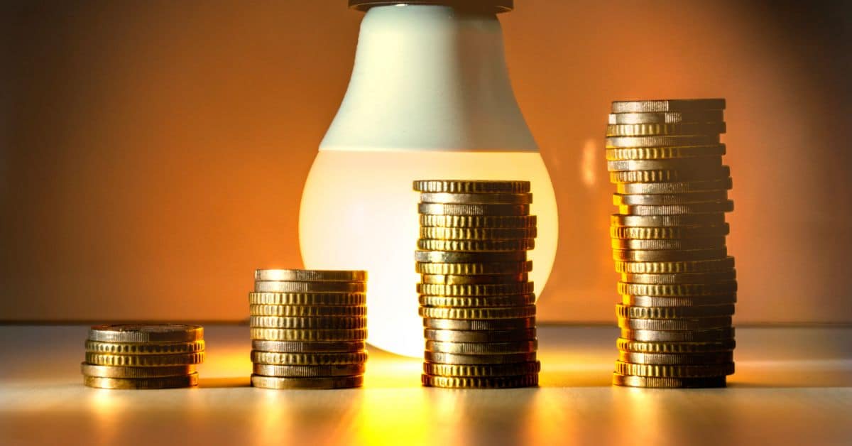 Stacked coins with a lightbulb symbolizing solar energy savings for Cape Town homeowners.