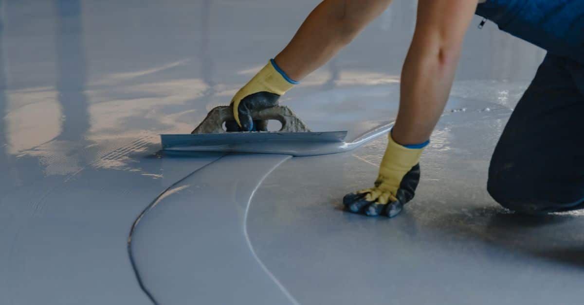 Skilled worker applying epoxy coating on a smooth concrete floor in Cape Town.