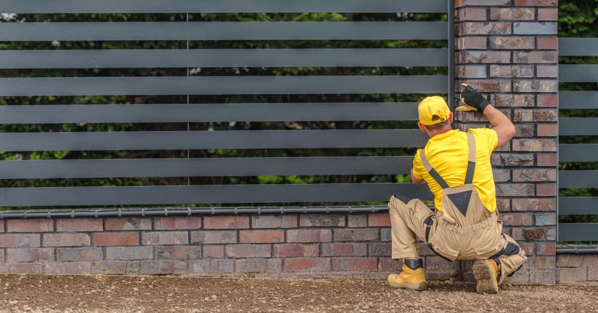Worker installing a modern boundary wall with horizontal slats in Cape Town.