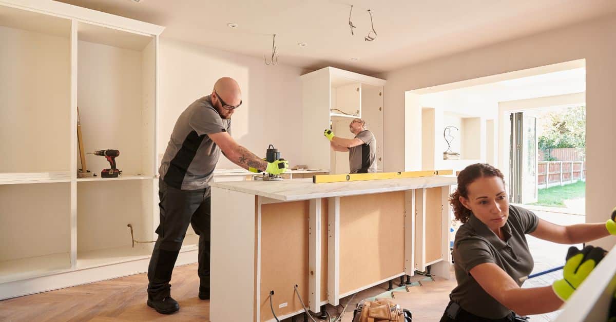 Renovation contractors installing kitchen cabinets for a home remodeling project.
