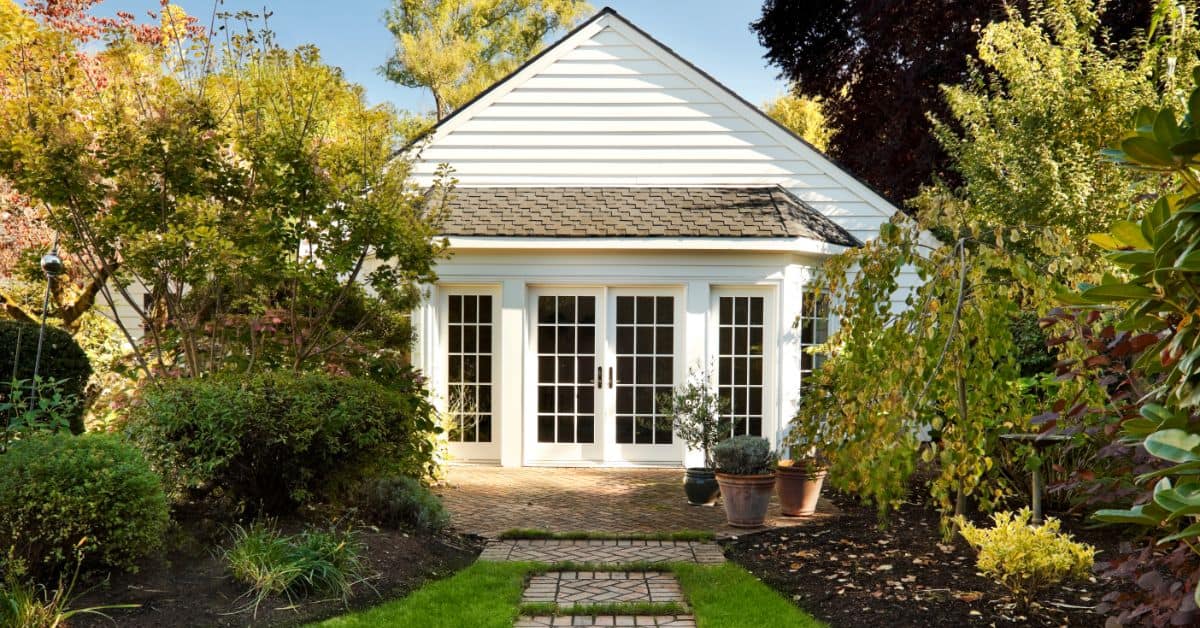 Charming backyard granny flat with white exterior and garden setting.