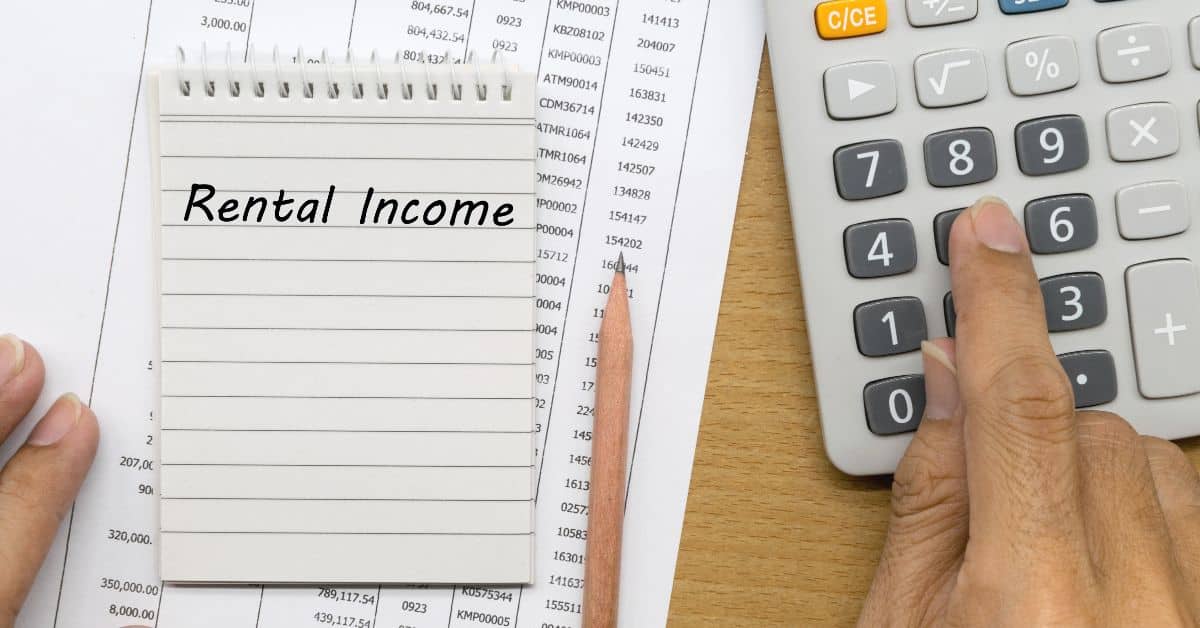 Person calculating rental income with calculator and financial documents.