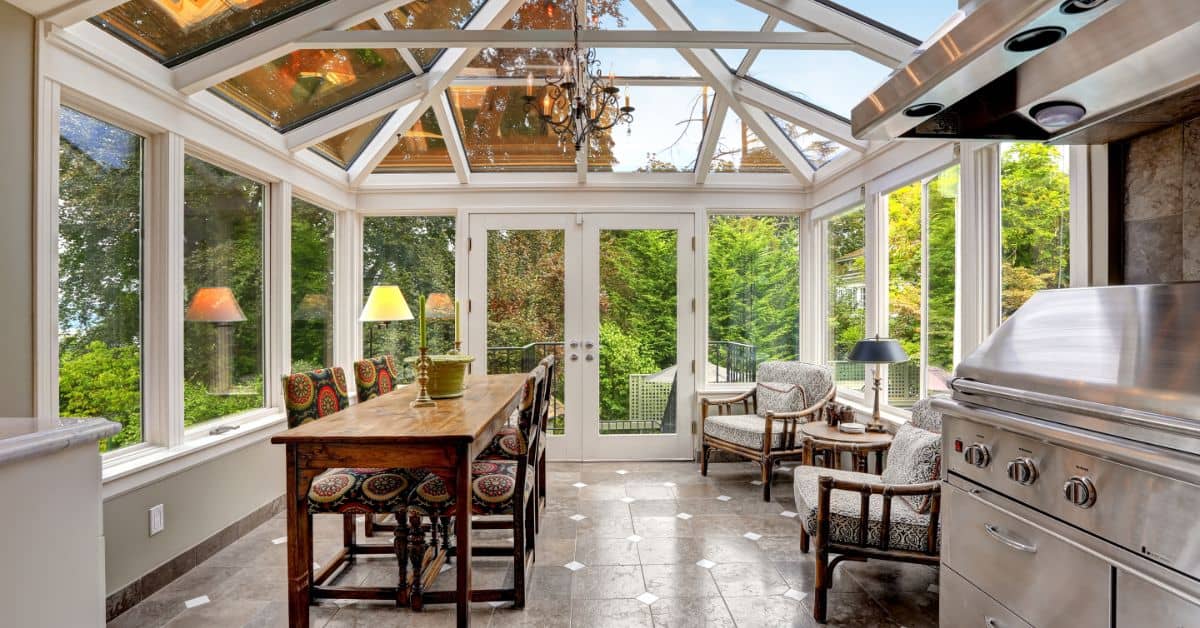 Bright sunroom with large windows and glass ceiling overlooking lush greenery. Perfect for relaxing.