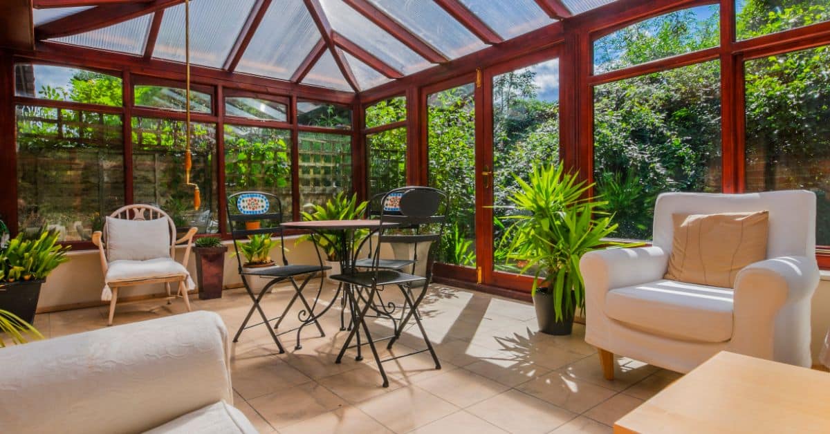 Bright sunroom with glass walls and cozy seating area.