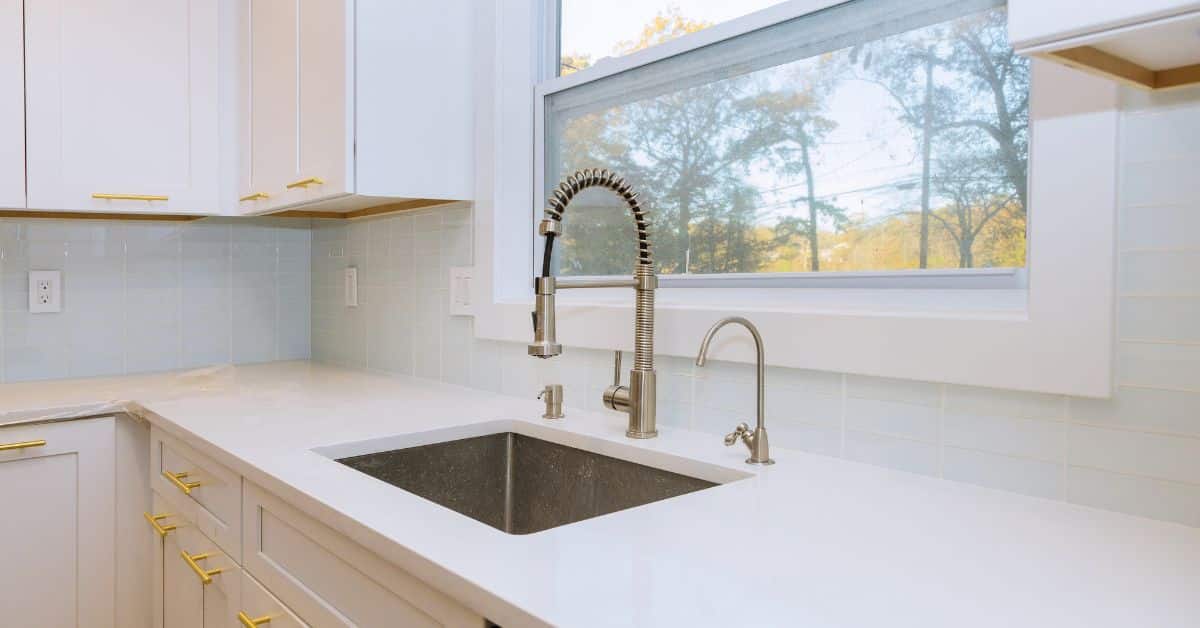 Bright modern kitchen featuring sleek white cabinetry and large window.
