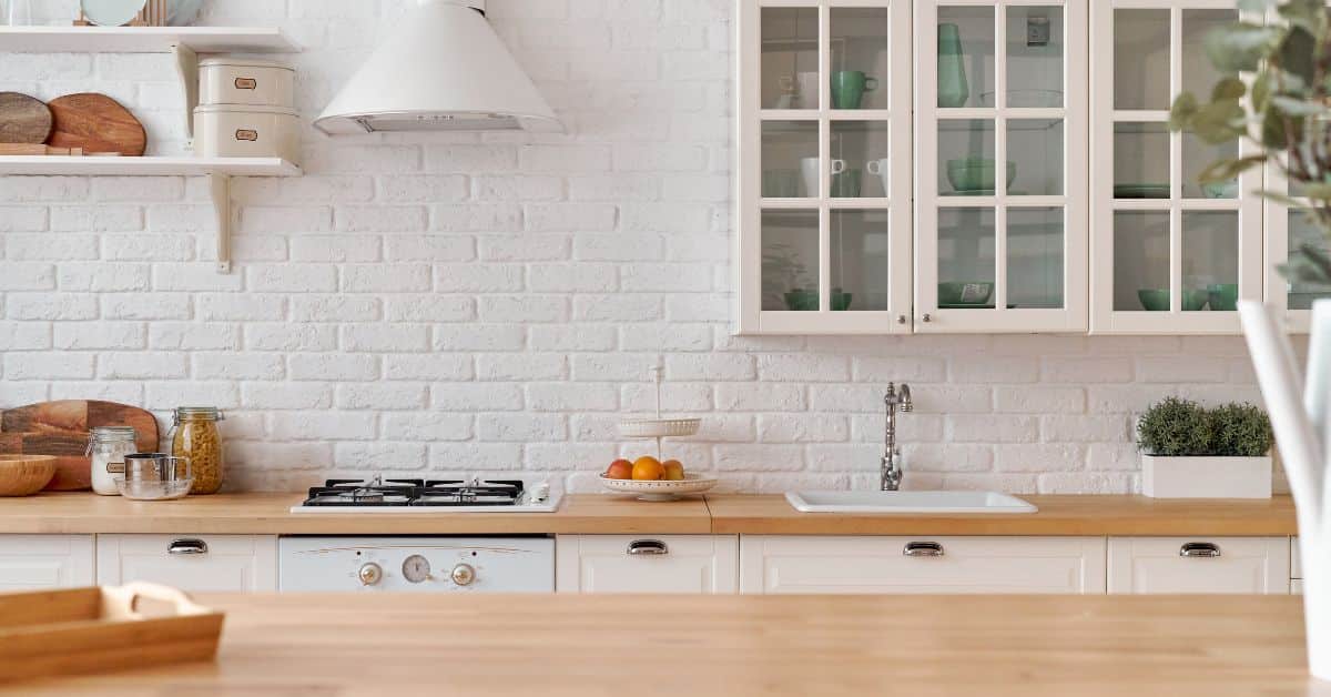 Modern white kitchen with island, large windows, and elegant decor.