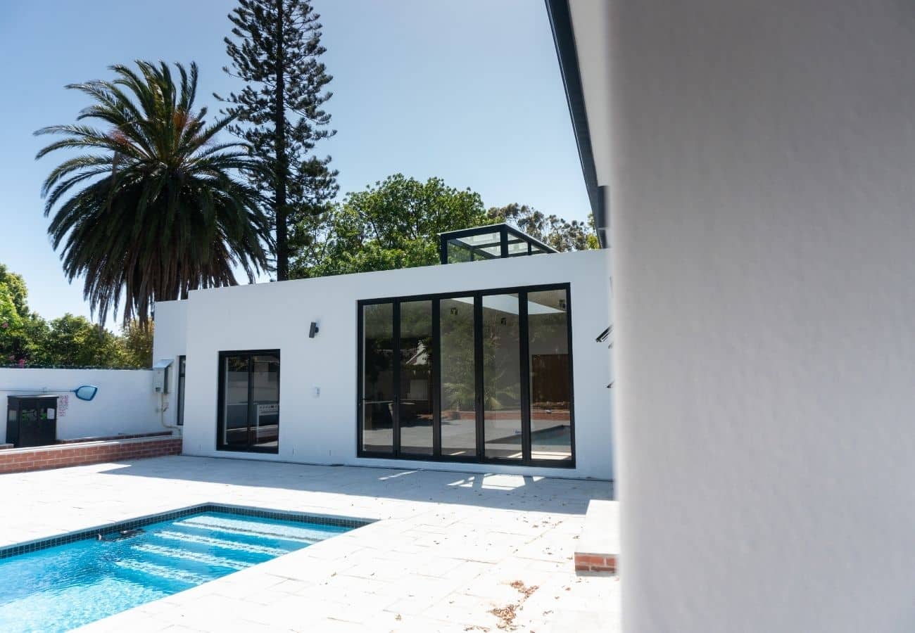 Modern white house with pool and large glass doors for outdoor living.