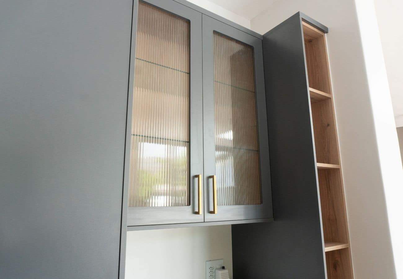 Gray and wood kitchen cabinets with glass doors and open shelving.