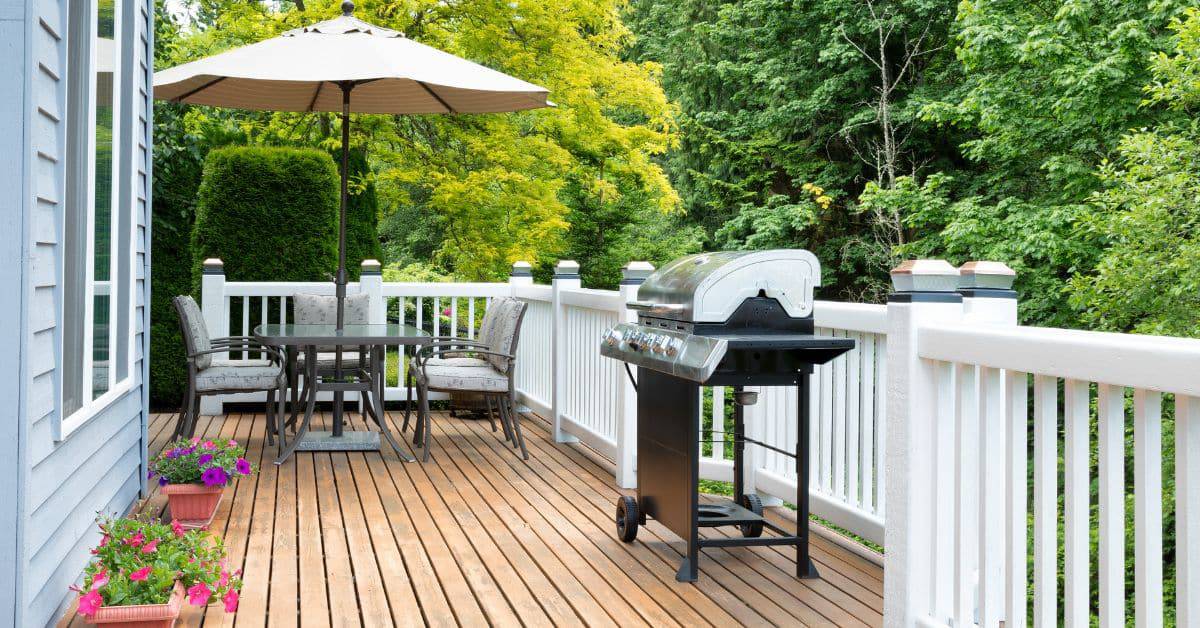 Outdoor entertainment area featuring a wooden deck, grill, and patio furniture for relaxing and host.