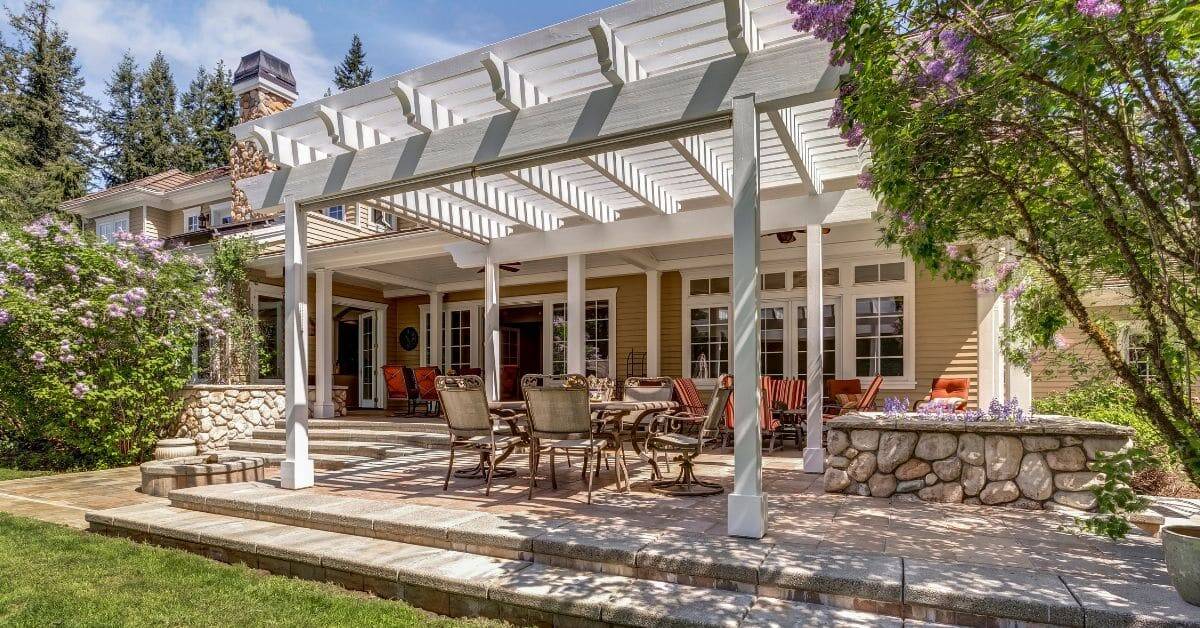Beautiful outdoor entertainment area featuring a stylish pergola, comfortable seating, and lush land.