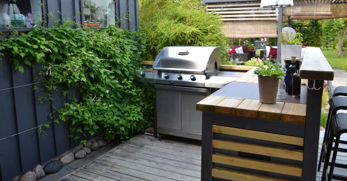 Outdoor kitchen setup featuring a stainless steel grill and wooden counter for patio cooking.