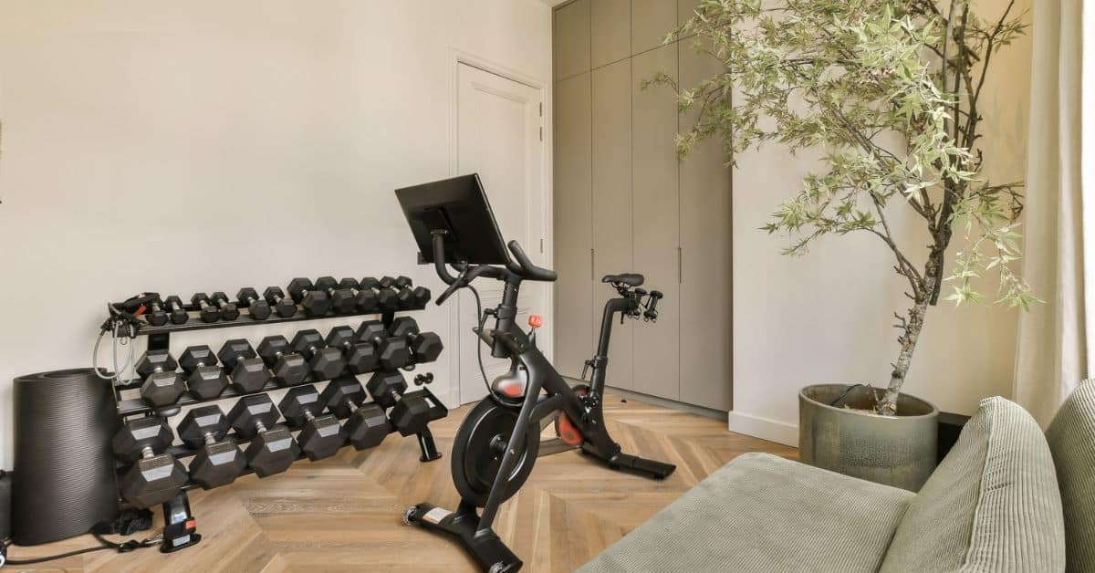 Home gym setup with dumbbells, exercise bike, and workout space for fitness enthusiasts.
