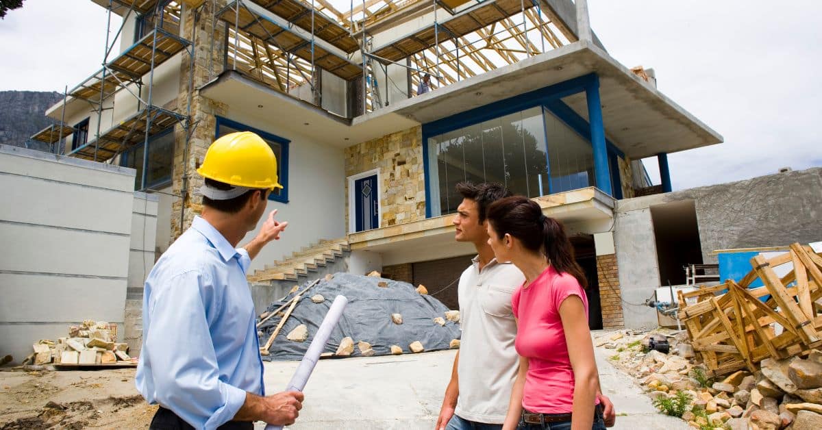 Couple talking to contractor with a house being built in the background