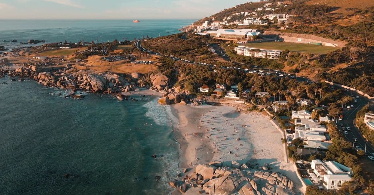 Aerial view of a construction site along Cape Town's coastline with scenic ocean and hillside backdr.