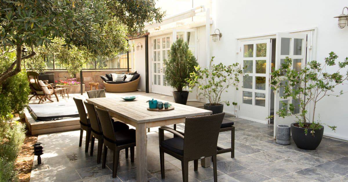 Outdoor patio with dining table, chairs, and potted plants for a relaxing backyard space.