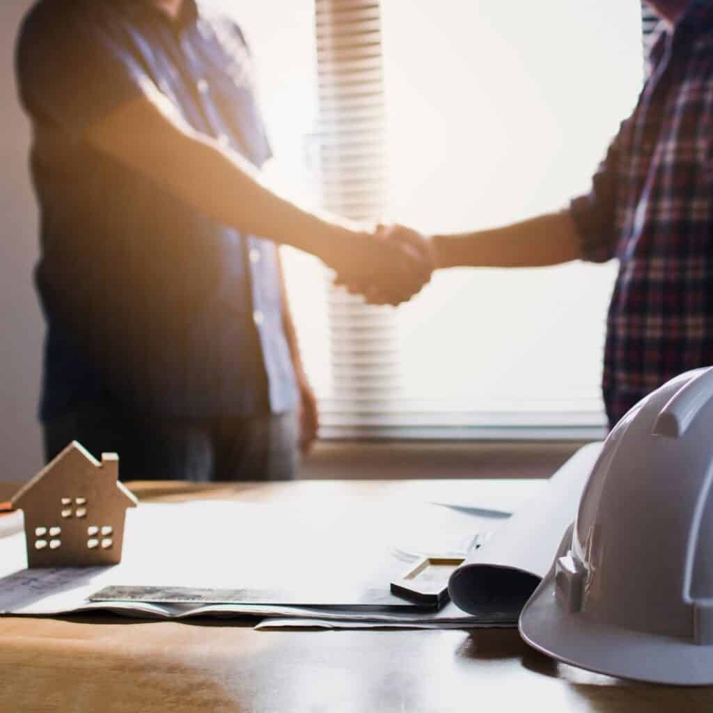 Handshake between builder and client in a home construction meeting.