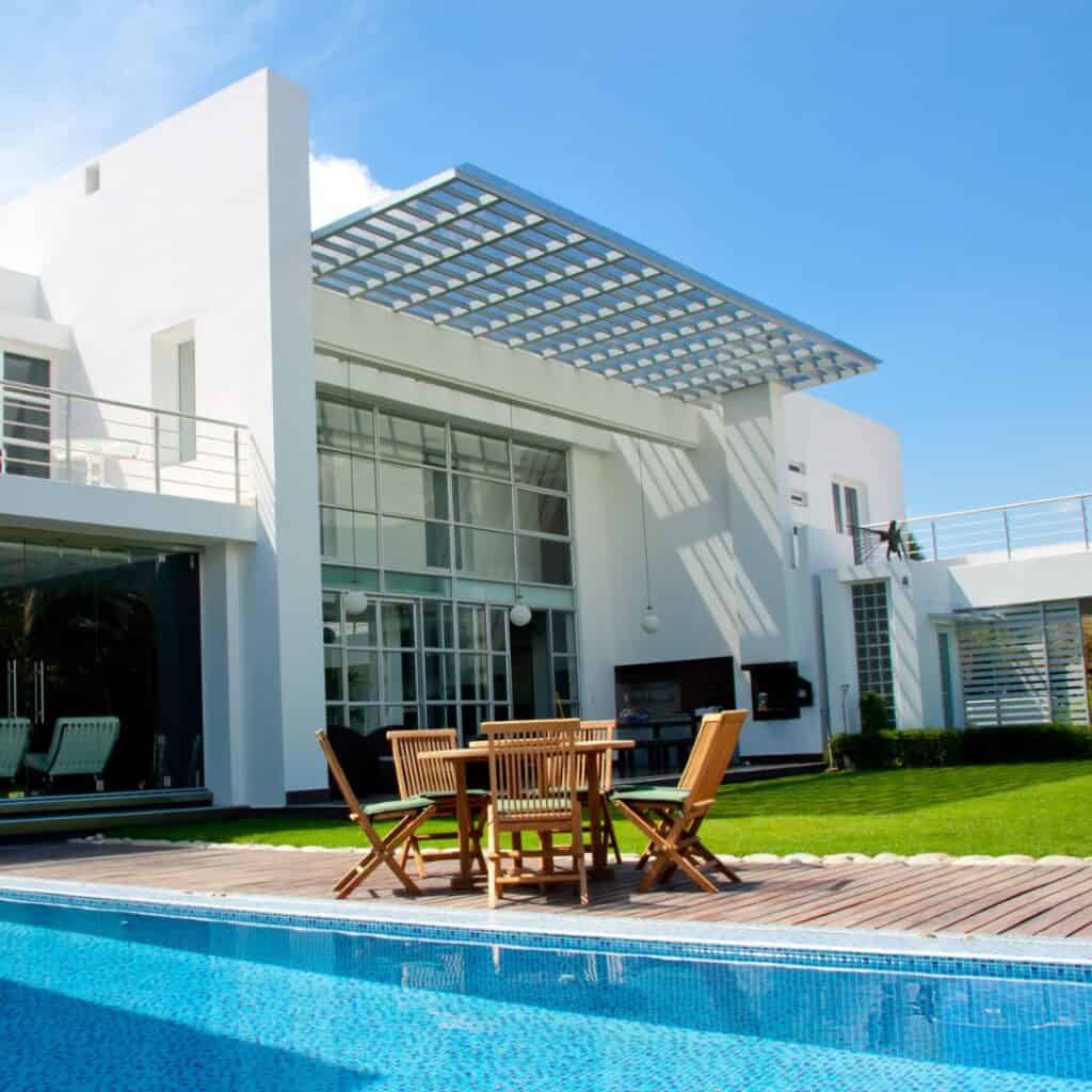 Contemporary white home featuring a pool and outdoor dining space under a pergola.
