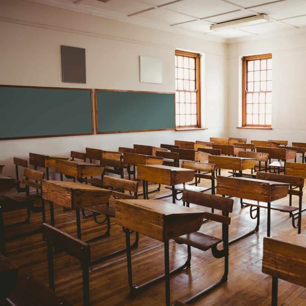 School classroom with wooden desks and large windows for natural light.